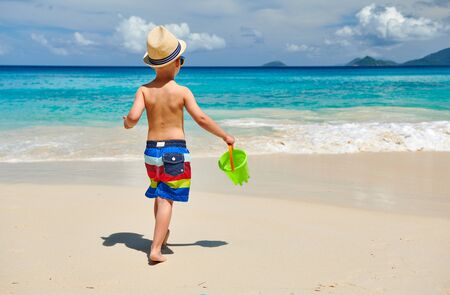 Three year old toddler boy playing with beach toys on beach. Summer family vacation at Seychelles, Mahe.の写真素材