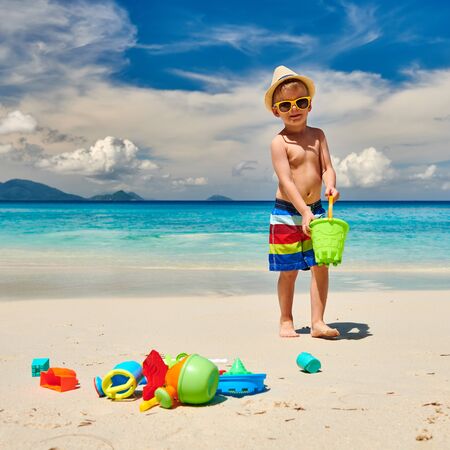 Three year old toddler boy playing with beach toys on beach. Summer family vacation at Seychelles, Mahe.の写真素材