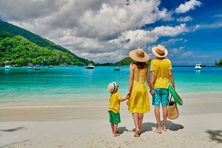 Family on beach, young couple in yellow with three year old boy. Summer vacation at Seychelles. Port Launay, Mahe. の写真素材