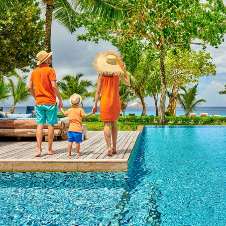 Family by poolside, young couple with three year old toddler boy. Resort swimming pool at Mahe, Seychelles.の写真素材