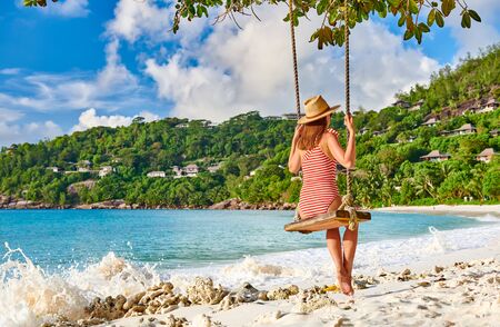Woman swinging at tropical beach, Petite Anse, Mahe, Seychelles.の写真素材