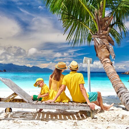 Family on beautiful Petite Anse beach, young couple with three year old toddler boy sitting on sun bed. Summer vacation at Seychelles, Mahe.の写真素材