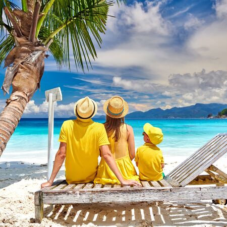 Family on beautiful Petite Anse beach, young couple with three year old toddler boy sitting on sun bed. Summer vacation at Seychelles, Mahe.の写真素材