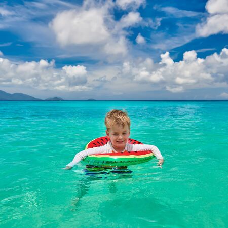 Three year old toddler boy on beach at Seychelles swimming with inflatable ringの写真素材