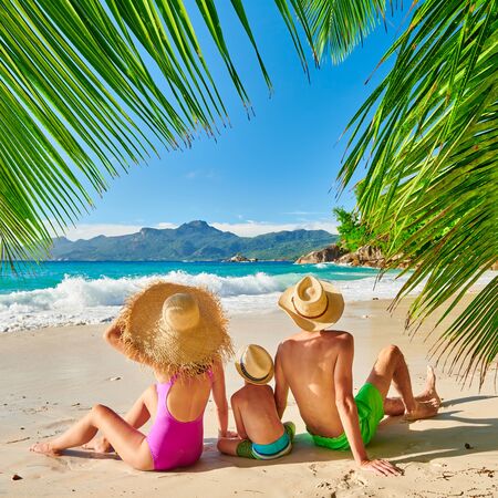 Family on beautiful Anse Soleil beach with palm tree, young couple with three year old toddler boy. Summer vacation at Seychelles, Mahe.の写真素材
