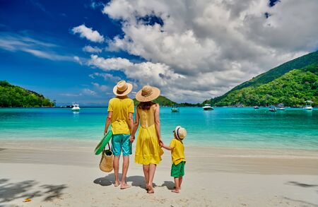 Family on beach, young couple in yellow with three year old boy. Summer vacation at Seychelles. Port Launay, Mahe.の写真素材
