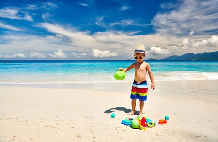 Three year old toddler boy playing with beach toys on beach. Summer family vacation at Seychelles, Mahe.の写真素材