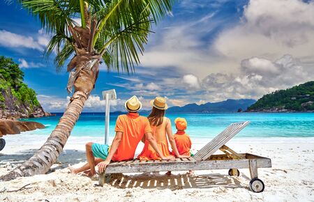 Family on beautiful Petite Anse beach, young couple with three year old toddler boy sitting on sun bed. Summer vacation at Seychelles, Mahe.の写真素材