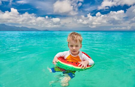 Three year old toddler boy on beach at Seychelles swimming with inflatable ringの写真素材