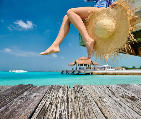 Woman sitting on wooden beach jetty. Summer vacation at Maldives.の写真素材