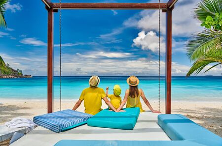 Family on beautiful Petite Anse beach, young couple in yellow with three year old toddler boy. Summer vacation at Seychelles, Mahe.の写真素材