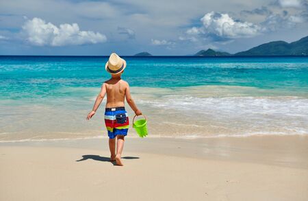 Three year old toddler boy playing with beach toys on beach. Summer family vacation at Seychelles, Mahe.の写真素材