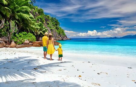 Family on beautiful Petite Anse beach, young couple in yellow with three year old toddler boy. Summer vacation at Seychelles, Mahe.の写真素材