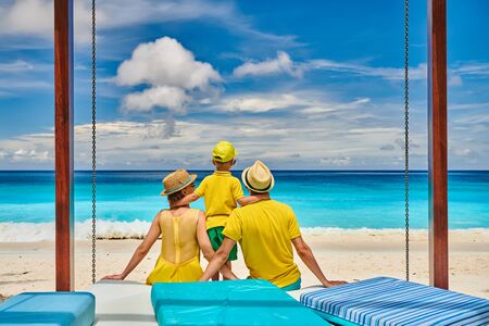 Family on beautiful Petite Anse beach, young couple in yellow with three year old toddler boy. Summer vacation at Seychelles, Mahe.の写真素材