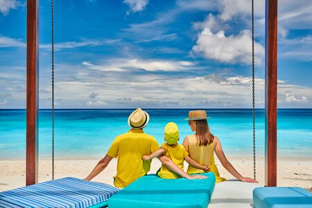 Family on beautiful Petite Anse beach, young couple in yellow with three year old toddler boy. Summer vacation at Seychelles, Mahe.の写真素材