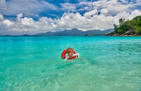Three year old toddler boy on beach at Seychelles swimming with inflatable ringの写真素材