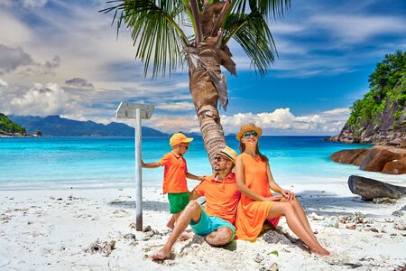 Family on beautiful Petite Anse beach, young couple with three year old toddler boy sitting on palm tree. Summer vacation at Seychelles, Mahe.の写真素材