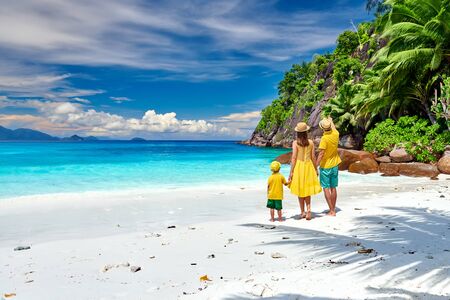 Family on beautiful Petite Anse beach, young couple in yellow with three year old toddler boy. Summer vacation at Seychelles, Mahe.の写真素材
