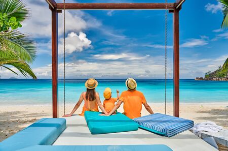 Family on beautiful Petite Anse beach, young couple in orange with three year old toddler boy. Summer vacation at Seychelles, Mahe.の写真素材