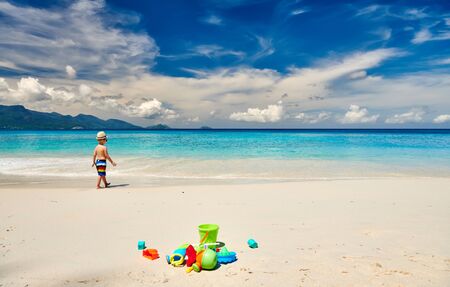 Three year old toddler boy playing with beach toys on beach. Summer family vacation at Seychelles, Mahe.の写真素材