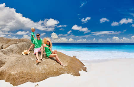 Family sitting on rock on beautiful Anse Intendance beach, young couple in green with three year old toddler boy. Summer vacation at Seychelles, Mahe.の写真素材