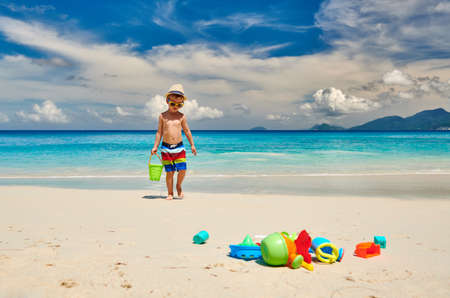 Three year old toddler boy playing with beach toys on beach. Summer family vacation at Seychelles, Mahe.の写真素材