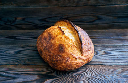Freshly baked homemade tartine bread on dark wooden tableの写真素材
