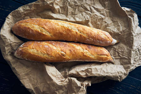 Freshly baked homemade baguette bread on dark wooden tableの写真素材