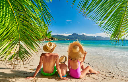 Family on beautiful Anse Soleil beach with palm tree, young couple with three year old toddler boy. Summer vacation at Seychelles, Mahe.の写真素材