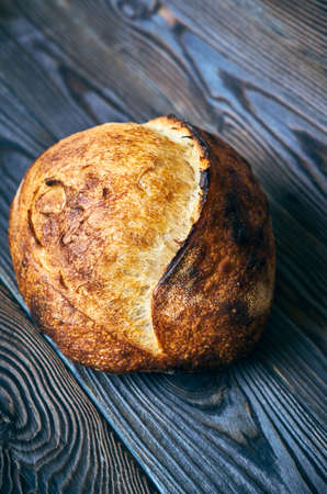 Freshly baked homemade tartine bread on dark wooden tableの写真素材