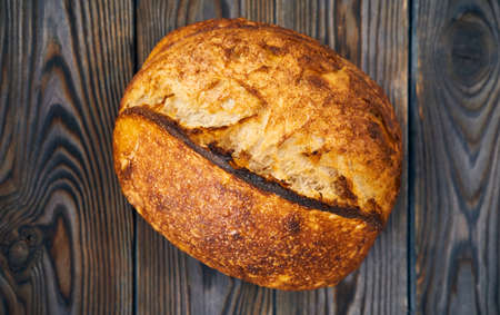 Freshly baked homemade tartine bread on dark wooden table