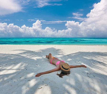 Woman in bikini at tropical beach under the palm tree shadowの写真素材