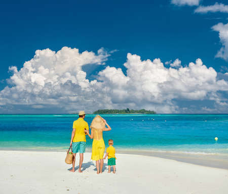 Family on beach, young couple in yellow with three year old boy. Summer vacation at Maldives.の写真素材