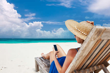 Young woman in hat with mobile phone at the beachの写真素材