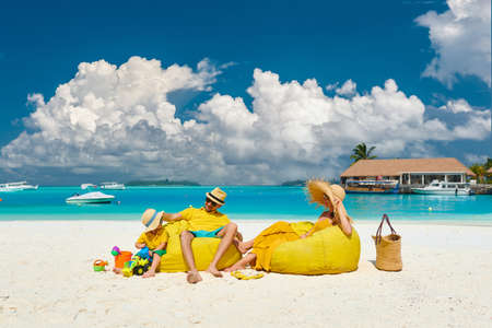 Family on beach, young couple in yellow with three year old boy. Summer vacation at Maldives.の写真素材