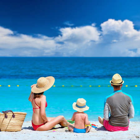 Family on beach. Two year old toddler boy playing with beach toys with mother and father on beach.の写真素材