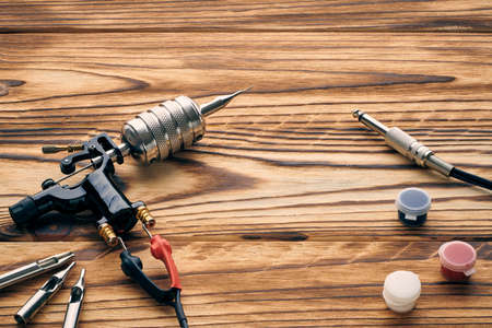 Tattoo machine, tools and supplies over wooden background. Tattoo studio.