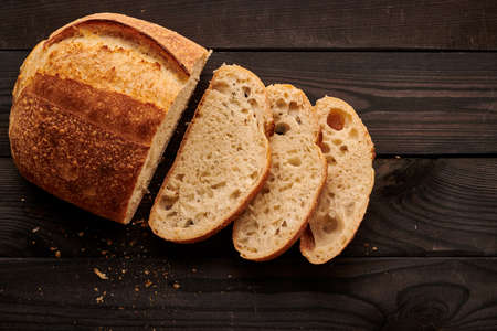 Freshly baked homemade tartine bread on dark wooden tableの写真素材