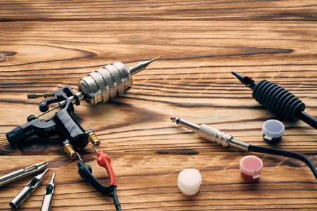 Tattoo machine, tools and supplies over wooden background. Tattoo studio.の写真素材