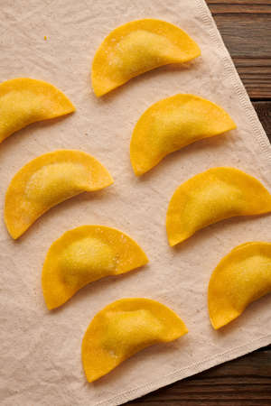 Tasty raw homemade ravioli pasta with spinach and ricotta on wooden rustic background. Process of making Italian ravioli.の写真素材