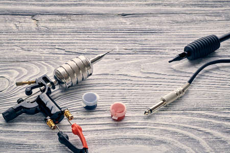 Tattoo machine, tools and supplies over wooden background. Tattoo studio.の写真素材