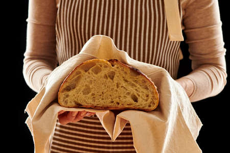 Baker woman holding rustic organic loaf of tartine homemade bread in handsの写真素材