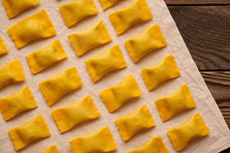 Tasty raw homemade ravioli pasta with spinach and ricotta on wooden rustic background. Process of making Italian ravioli.の写真素材