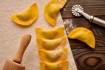 Tasty raw homemade ravioli pasta with spinach and ricotta on wooden rustic background. Process of making Italian ravioli.の写真素材
