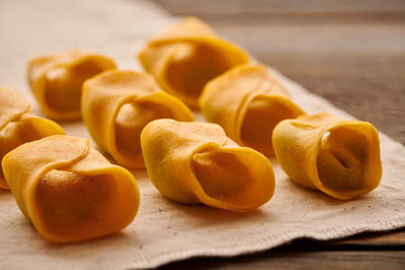 Tasty raw homemade ravioli pasta with spinach and ricotta on wooden rustic background. Process of making Italian ravioli.の写真素材
