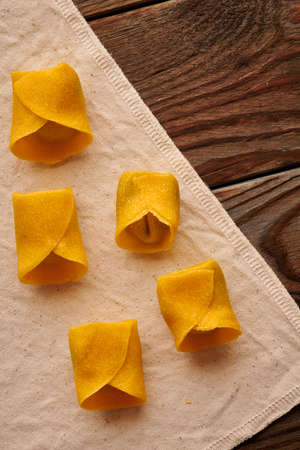 Tasty raw homemade ravioli pasta with spinach and ricotta on wooden rustic background. Process of making Italian ravioli.の写真素材