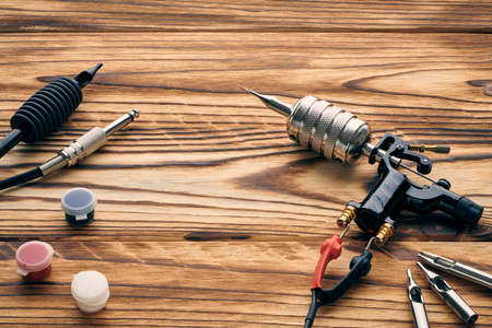 Tattoo machine, tools and supplies over wooden background. Tattoo studio.の写真素材