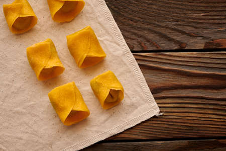 Tasty raw homemade ravioli pasta with spinach and ricotta on wooden rustic background. Process of making Italian ravioli.の写真素材