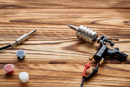 Tattoo machine, tools and supplies over wooden background. Tattoo studio.の写真素材