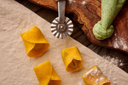 Tasty raw homemade ravioli pasta with spinach and ricotta on wooden rustic background. Process of making Italian ravioli.の写真素材